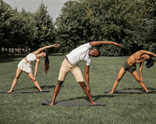 Diverse group of people of all ages practicing yoga outdoors.